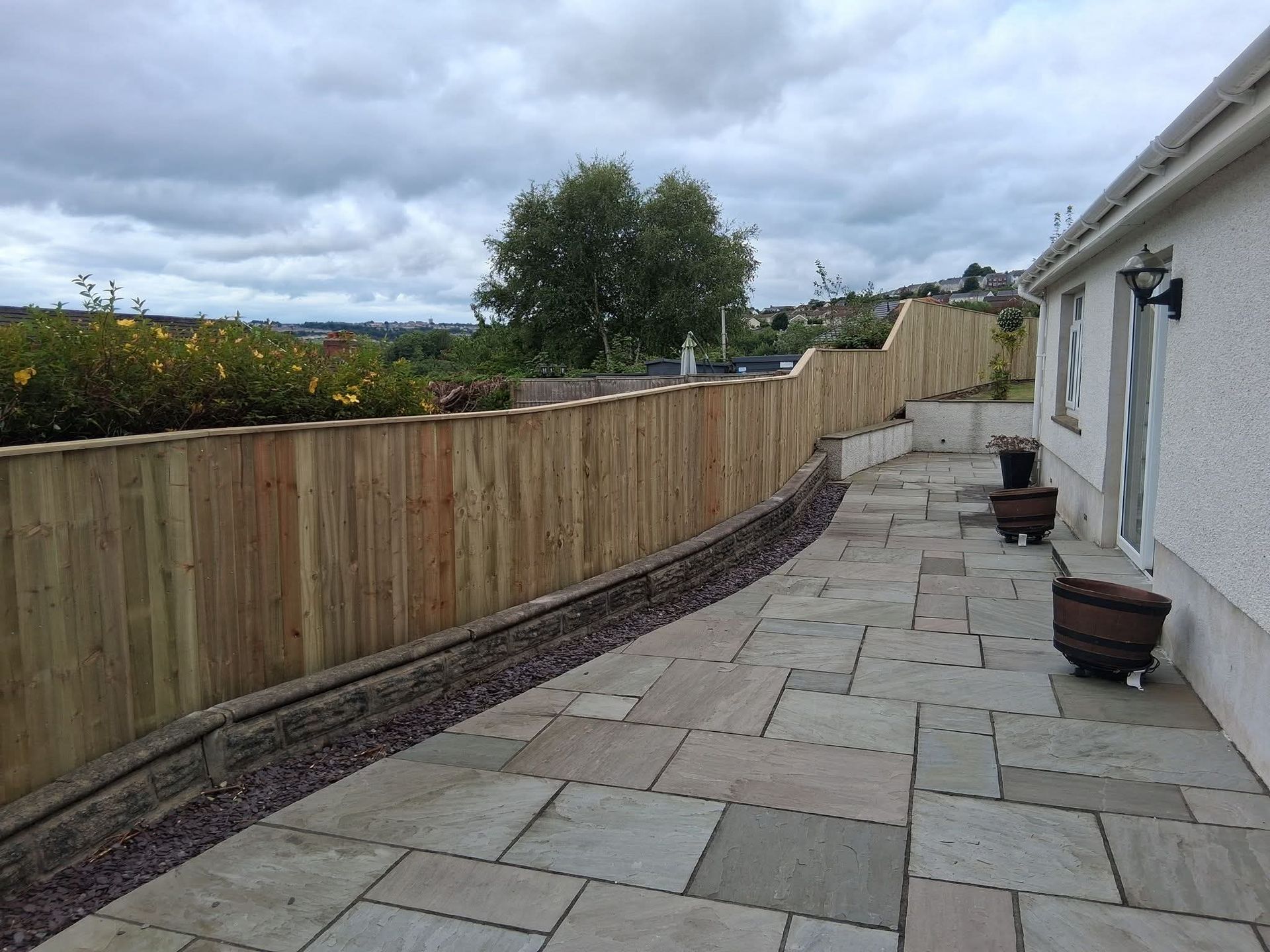 Long run of timber fencing following a curved garden boundary beside a paved path